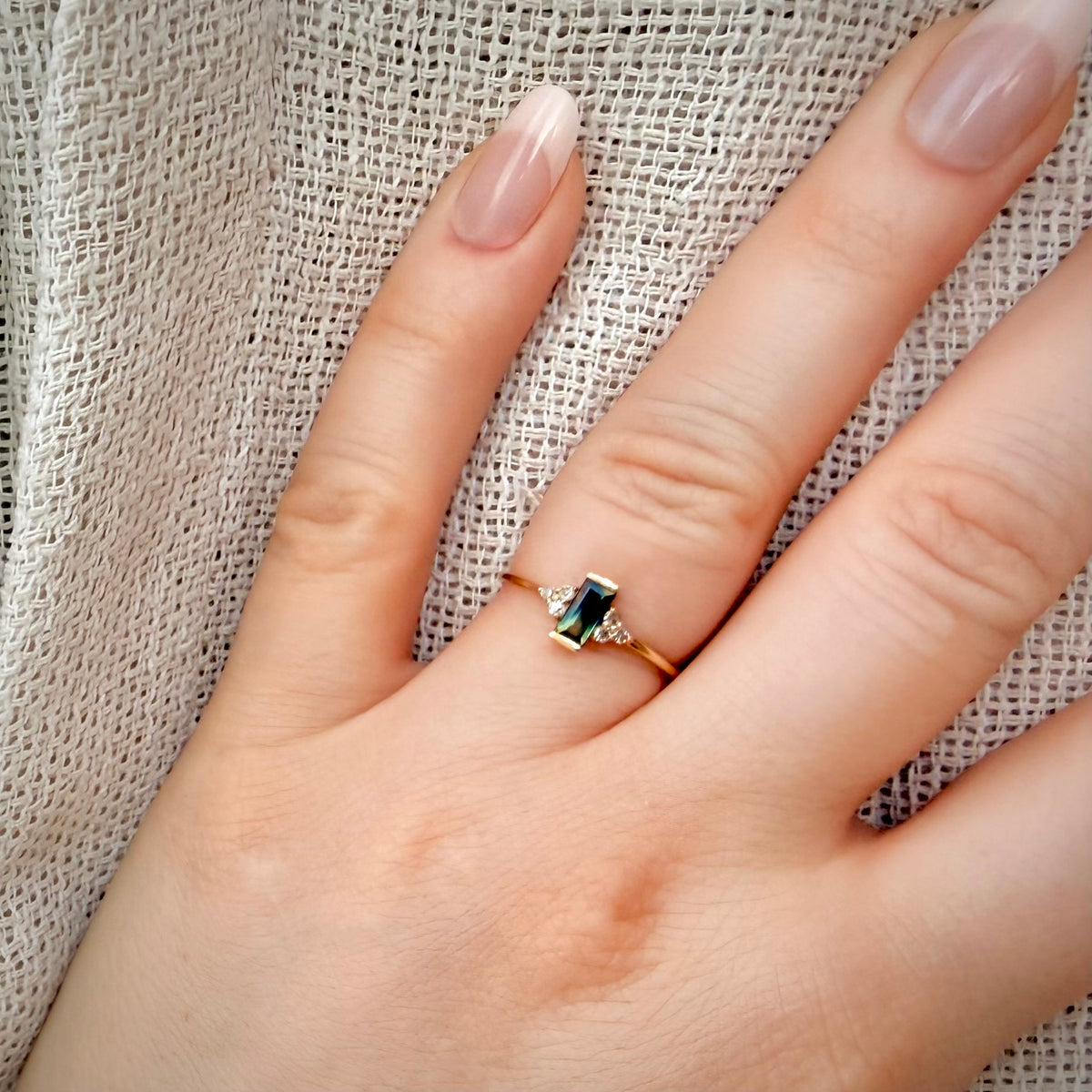 Kaksivärinen safiirisormus 0,49 ct – luonnontimantit 0,09 ct | 14K keltakulta sormessa pellavataustalla