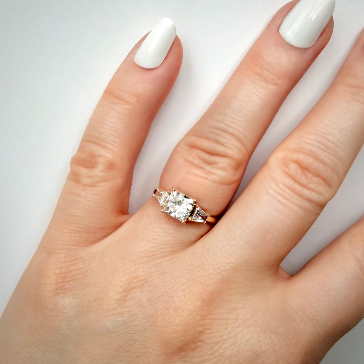 1,69 ct Princess Cut trilogy-timanttisormus sormessa valkoisella taustalla