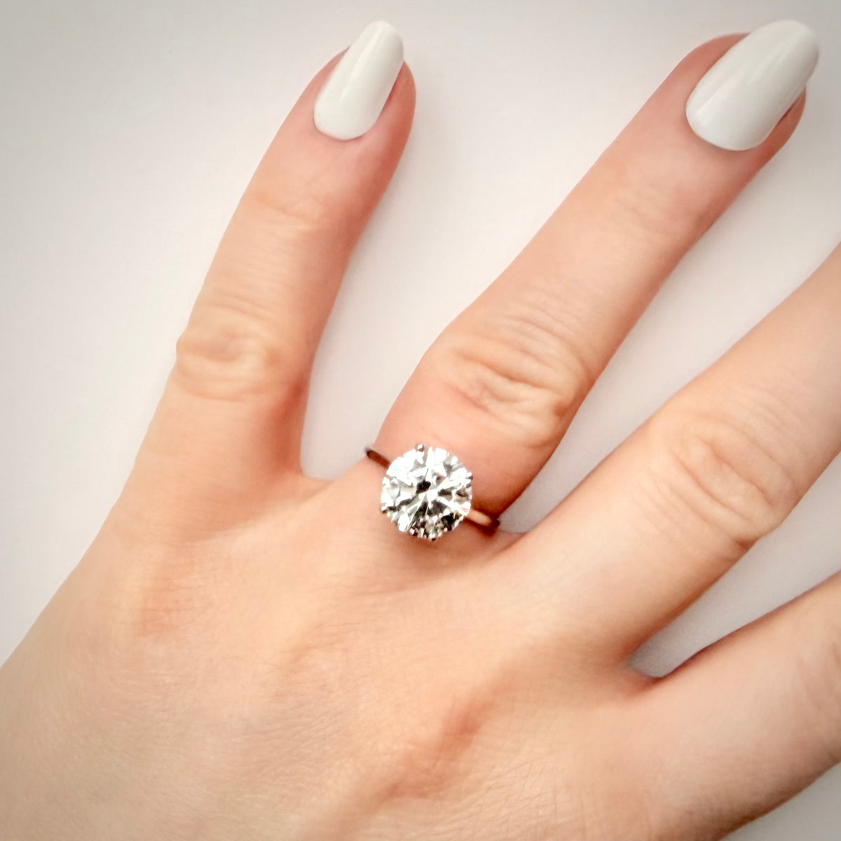 4,01 ct solitaire-timanttisormus sormessa valkoisella taustalla