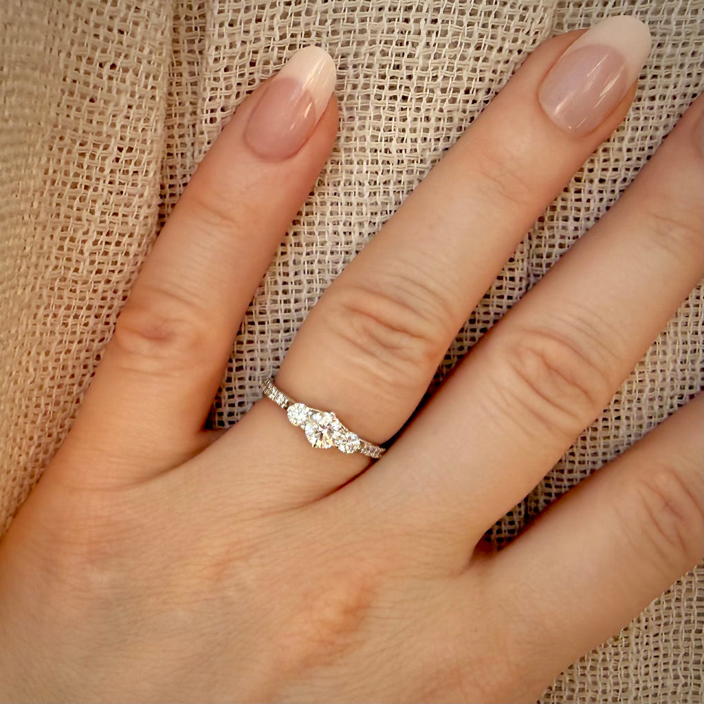 1,00 ct trilogy-timanttisormus sormessa pellavataustalla