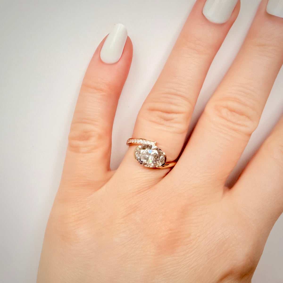2,80 ct East–West ovaali-timanttisormus sormessa valkoisella taustalla