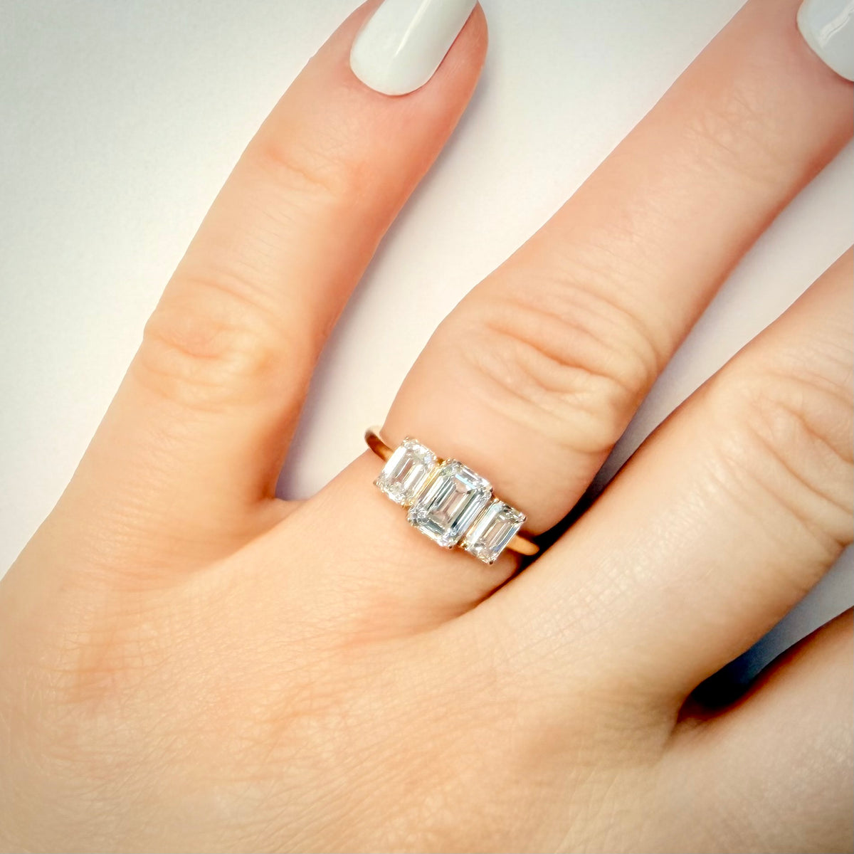 2,36 ct Emerald Cut trilogy-timanttisormus 14K | HRD kuva sormuksesta sormessa