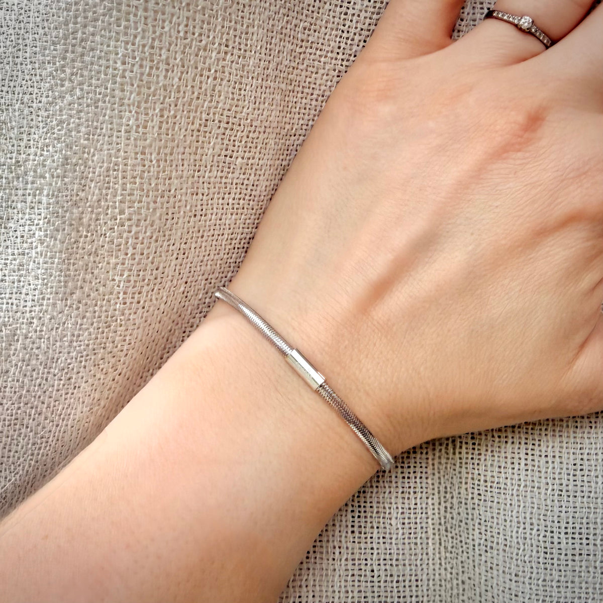 18K valkokultainen joustava mesh-rannekoru – Made in Italy ranteessa pellavataustalla