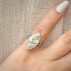 8,19 ct Marquise Cut -timanttisormus sormessa pellava taustalla