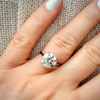 4,01 ct solitaire-timanttisormus sormessa pellava taustalla
