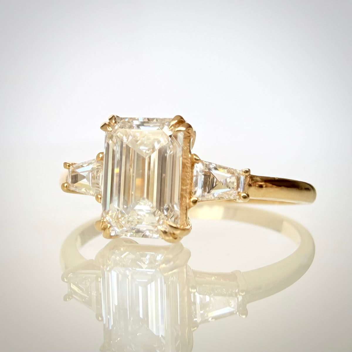 1,20 ct Emerald Cut trilogy-timanttisormus etu viistosta