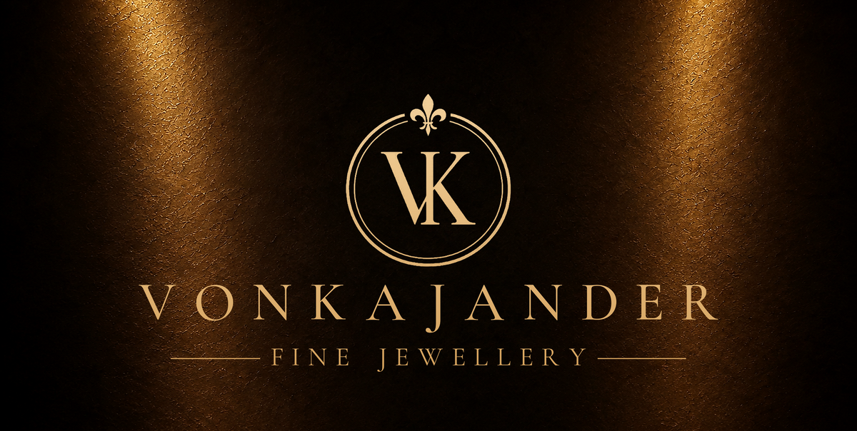 VonKajander Fine Jewellery Logo kullansävyisenä tummaa ruskeaa taustaa vasten